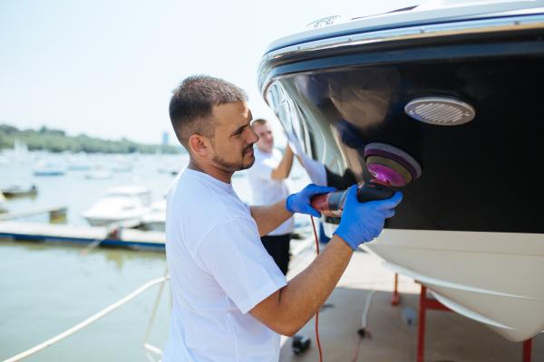 Marine technician buffing and polishing boat bottom at Beacon Bay Marina